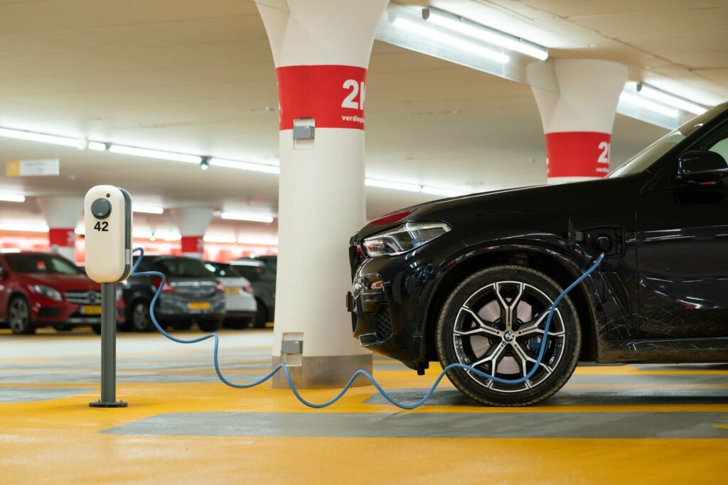 Black EV car being charged in a public parking garage